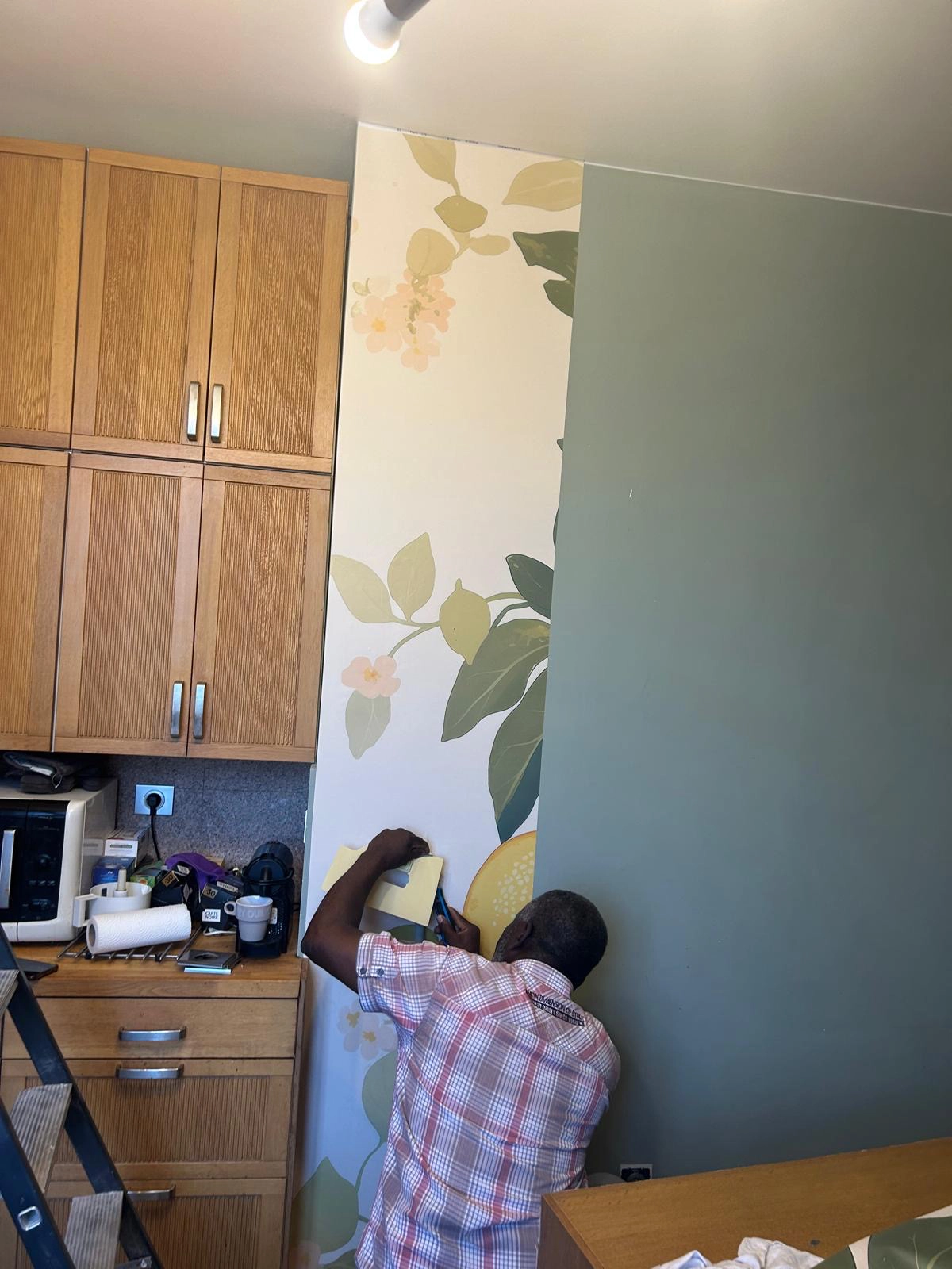 Pose du premier lé d'un papier peint panoramique à motif citronnier